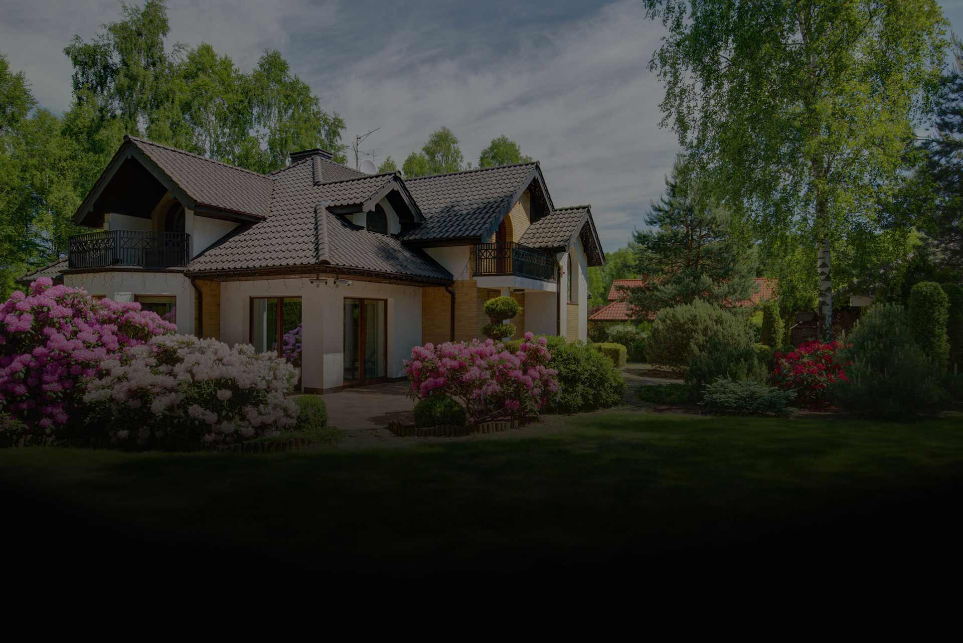 A large house surrounded by a spacious yard filled with colorful flowers in bloom.