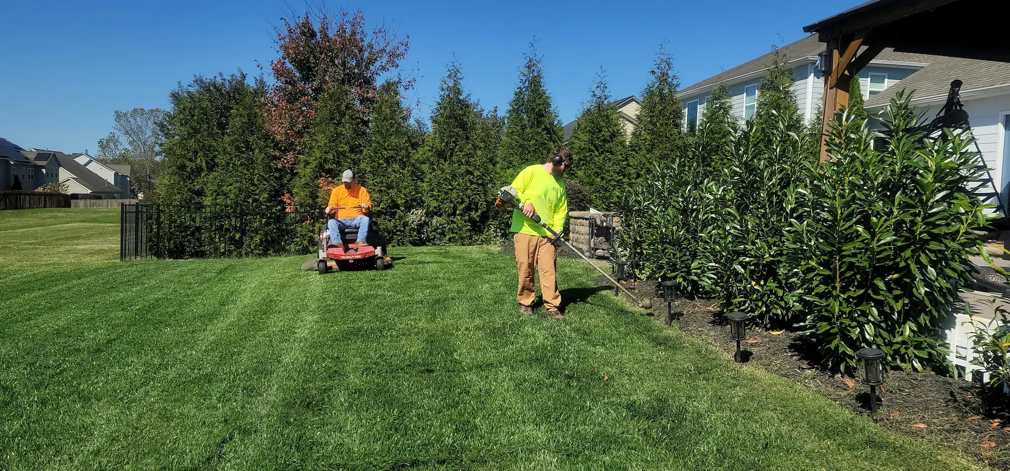 Landscape maintenance crew working on garden beds, lawn edging, or general yard care in a beautifully maintained outdoor space.